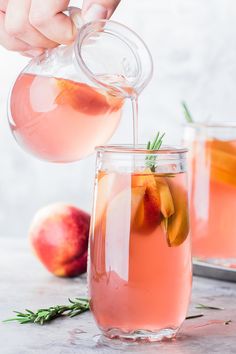 someone pouring pink gin and peach punch into a glass