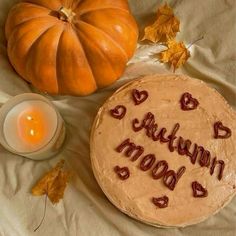 a cake with the words autumn mood written on it next to a candle and pumpkin