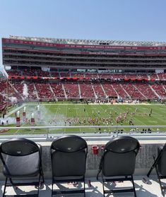 three empty chairs are sitting in front of an empty football stadium