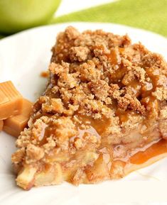 a close up of a slice of pie on a plate with apples in the background