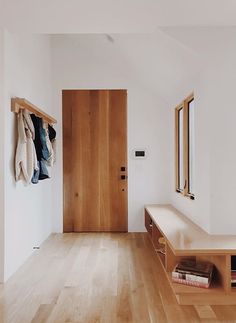 an empty room with wooden floors and coat racks on the wall next to a door