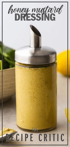 a jar filled with yellow liquid sitting on top of a table next to lemons