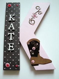 the letter k is made out of paper and has a cowboy boot on it next to a sign that says kate