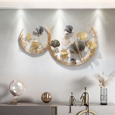 two circular metal wall art pieces on a white shelf in front of a gray wall