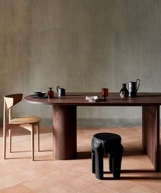 a wooden table with two chairs next to it and coffee mugs on the table