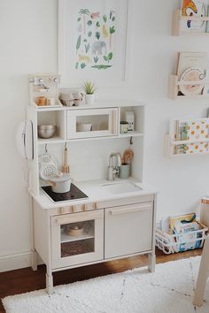 a white play kitchen with lots of shelves and cupboards on the wall above it