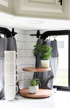 three tiered shelves with plants on them in the corner of a white room next to a window