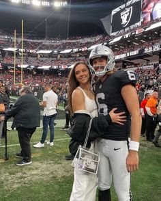 a man and woman standing next to each other on a field at a football game