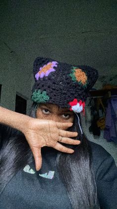 a woman with her hand on the top of her head wearing a crocheted hat