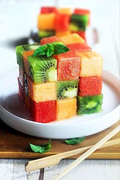 slices of fruit are arranged on a plate with chopsticks and watermelon