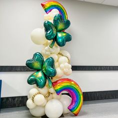 a bunch of balloons that are in the shape of a rainbow and shamrocks on top of each other