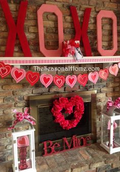 valentine's day mantel decorated with red and pink paper heart garlands, lanterns and candles