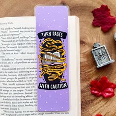 a bookmark with the words turn pages, hit caution on it next to an open book