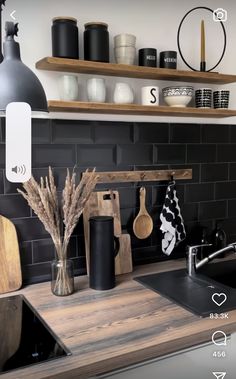 a kitchen with black tile and wooden counter tops is pictured in this image, there are various items on the shelves above the sink