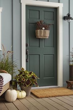 a green door with two planters on the porch