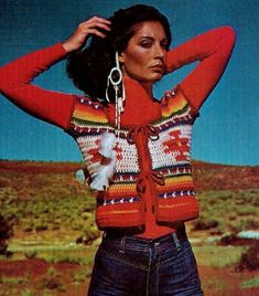 a woman with her hands on her head wearing a colorful cardigan sweater and jeans