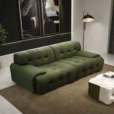 a green couch sitting on top of a carpeted floor next to a white table