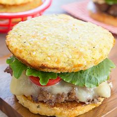 a cheeseburger with meat, lettuce and tomato on a cutting board