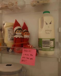 two elf dolls sitting on top of a shelf next to milk and yogurt