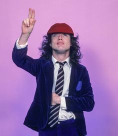 a man with long hair wearing a suit and tie holding his hand up in the air