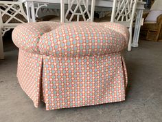 an upholstered ottoman sits in front of a dining room table