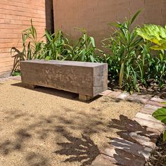 a concrete bench sitting in the middle of a garden next to a brick wall and green plants