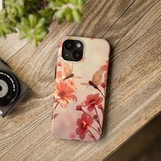 a phone case with flowers on it next to a camera