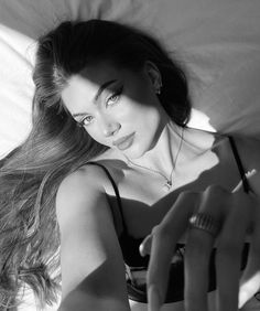 black and white photograph of a woman laying in bed with her hand on the pillow