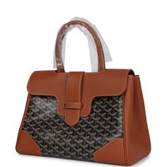 This Goyard Saigon soft tote is in black Goyardine coated canvas and tan chevroches calfskin with palladium hardware, contrast stitching, features two double rolled top handles, signature saigon leather strap and loop closure, a cutout in the top of the flap for the handle to fit through.The interior is lined is white canvas and tan chevroches calfskin, single floating pocket and a wooden detail on back of bag with palladium studs.Origin: FranceCondition: New and never worn (plastic on handles)Accompanied by: Goyard box, dustbag, felt, ribbon and carebookMeasurements: 13" x 9.8"x 6" Luxury Brown Epsom Leather Bag, High-end Leather Bag With Leather Trim, Business Bags With Leather Lining And Coated Canvas, Brown Monogram Canvas Bag With Palladium Hardware, Luxury Bags With Leather Trim And Epsom Leather, Designer Brown Epsom Leather Bags, High-end Brown Epsom Leather Bags, Brown Epsom Leather Bag With Detachable Handle, Brown Signature Coated Canvas Bag With Leather Lining