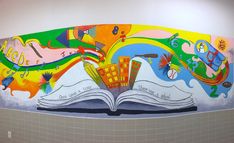 a mural on the side of a wall in a public restroom, depicting an open book