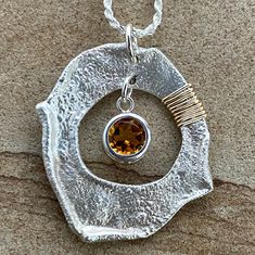 The flair of 14-karat gold fill accents adds a shimmer to the handcrafted Citrine Pendulum. This reticulated silver work of art hangs from a sterling chain and showcases a round citrine stone within a smooth, sleek housing. Energize your aura with the warming influence of citrine, balanced with the cool precision of artisan-crafted silver jewelry. 8mm round citrine (about 1.8 tcw) 1.25"x1.5" reticulated sterling pendulum 14k gold fill accents adjustable (16"-24") sterling rope chain includes adj Modern Citrine Jewelry Gift, Modern Citrine Jewelry For Gift, Modern Amber Pendant Jewelry, Modern Citrine Jewelry With Polished Finish, Modern Citrine Gemstone Jewelry, Modern Amber Jewelry With Citrine, Modern Amber Citrine Jewelry, Unique Citrine Birthstone Jewelry, Hand Forged Amber Sterling Silver Jewelry