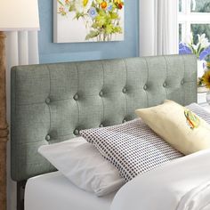 a bed with white sheets and blue walls in a bedroom next to a vase filled with flowers