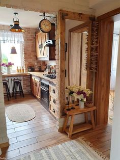 a kitchen with wooden cabinets and an open door leading to the dining room, which has a clock on the wall