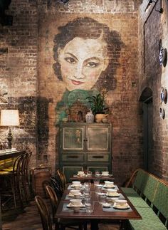 a dining room with brick walls and painted mural on the wall, along with green chairs