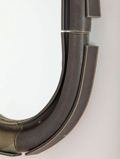 an oval mirror hanging on the wall next to a white wall with a black handle