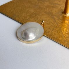 Estate/ vintage 14KT yellow gold genuine, Mabe Blister pearl omega/ pearl enhancer slide. Fits up to a 5mm depending upon the necklace/omega ORopens to fits (any size) in the space between your pearls or other beaded necklaces. Stamped / Hallmarked 14KT/585 14KT gold bezel encased Mabe pearl Measures: 45mm x 35mm Fits 5mm depending upon how flat your chain may be Weight: 17.50 grams Excellent condition No chain included Classic Pearl Charm Jewelry In Mother Of Pearl, Classic Mother Of Pearl Jewelry With Pearl Charm, Elegant Large Pendant Mother Of Pearl Jewelry, Classic Yellow Gold Mother Of Pearl Jewelry, Classic Mother Of Pearl Jewelry In Yellow Gold, Classic Yellow Gold Jewelry With Mother Of Pearl, Classic Jewelry With High Luster Round Pendant, Oval Pearl Pendant, Classic Round Pendant Jewelry With High Luster