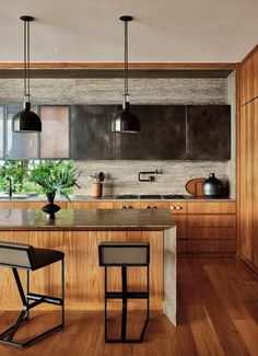 a kitchen with two stools and an island in front of the counter top that is made out of wood