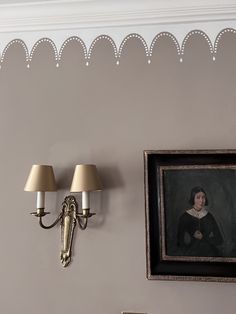 a painting on the wall next to two lamps and a framed photograph hanging on the wall