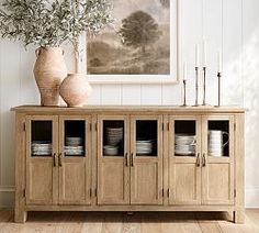 a wooden cabinet with plates and vases on top