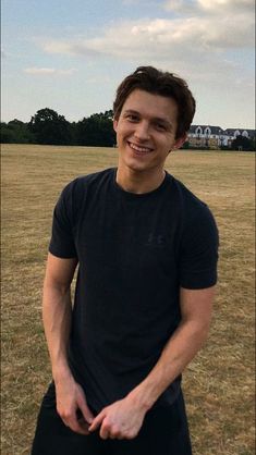 a young man is standing in the middle of a field