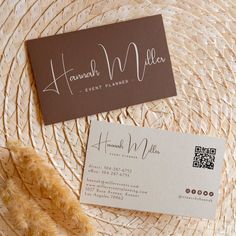 a business card sitting on top of a straw hat next to a brown and white business card