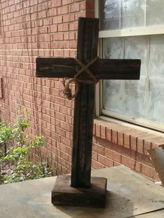 a wooden cross sitting on top of a table next to a brick wall and window