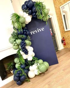 the balloon arch is decorated with green and white balloons, greenery, and berries