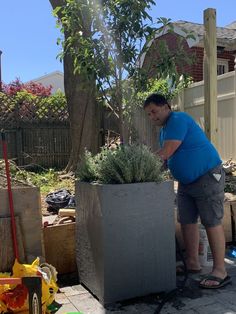 a man standing next to a planter filled with plants