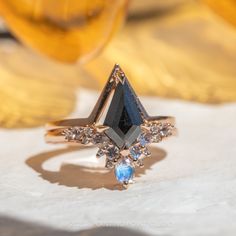 a diamond and blue topaz ring sits on a white piece of paper next to a yellow vase