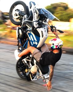 a man riding on the back of a motorcycle while holding onto it's wheel