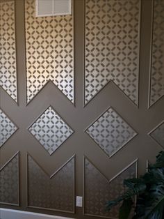 the wall is decorated with geometric designs on it's sides and has a plant in front of it