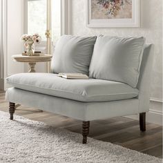 a white couch sitting on top of a wooden floor next to a table with flowers