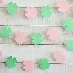 paper shamrocks are hanging on the wall with pink, green and white ones attached to them