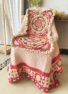 a crocheted blanket sitting on top of a chair next to a potted plant